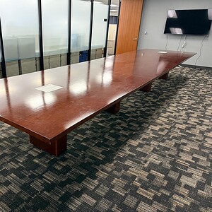 Conference room table with polished wood surface in a modern office setting.
