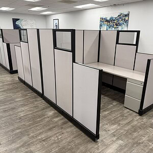 Modern office cubicles with beige and black panels in workspace.