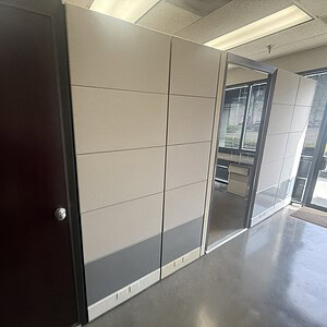 Office cubicle wall panels with glass door and window in modern workspace.
