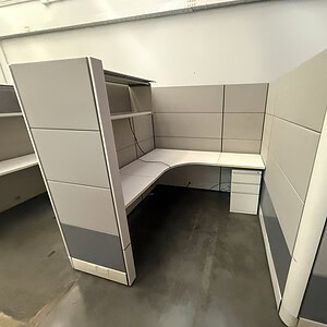 Office cubicle with fabric and perforated metal tiles for workspace privacy.