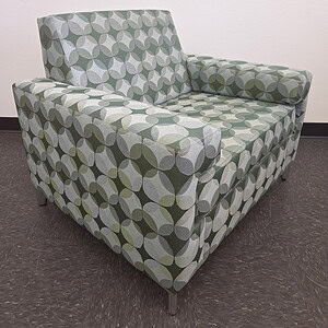 Modern patterned lounge chair with green, gray, and white geometric design.