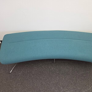 Teal ottoman bench with metal legs in modern office setting.