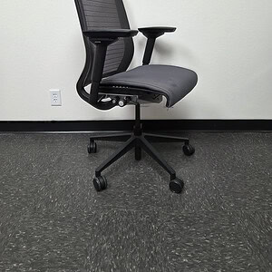 Black mesh back office chair with grey seat and adjustable arms.