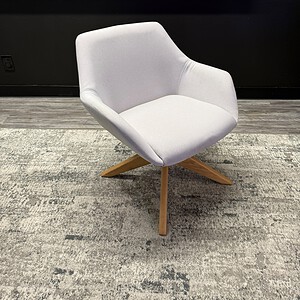Modern white lounge chair with wooden base in stylish interior setting.