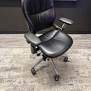 Black leather office chair with adjustable armrests and chrome base.