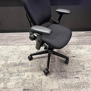 Black ergonomic office chair with adjustable armrests and lumbar support.