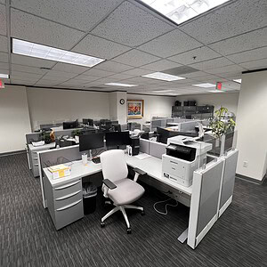 Open-plan office with cubicles featuring 12-inch glass stackers and ergonomic chairs.