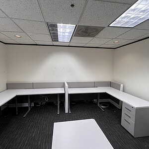 L-shaped benching stations for office workspace with wall-to-wall configuration.