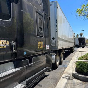 Semi truck with a large white trailer parked on a sunny day.