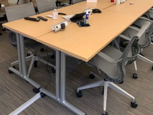 Modern conference table with chairs, power outlets, and remote controls in a professional meeting ro.