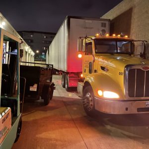 Heavy-duty yellow truck delivering containers for global shipping services.