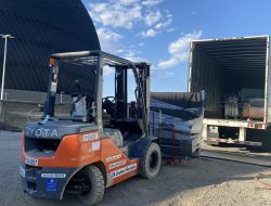 Forklift moving large wrapped items during office relocation.