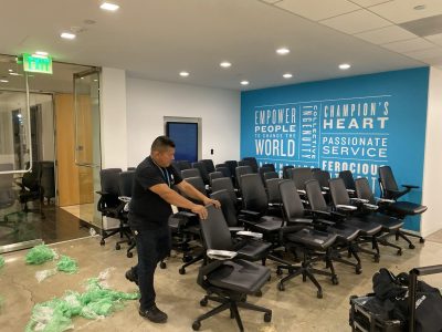 Office furniture liquidation sale with rows of black chairs in a modern conference room.