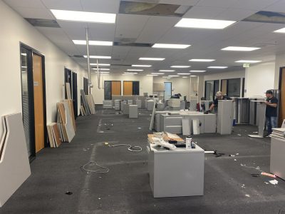 Office furniture liquidation with desks, cubicles, and chairs in a spacious commercial space.