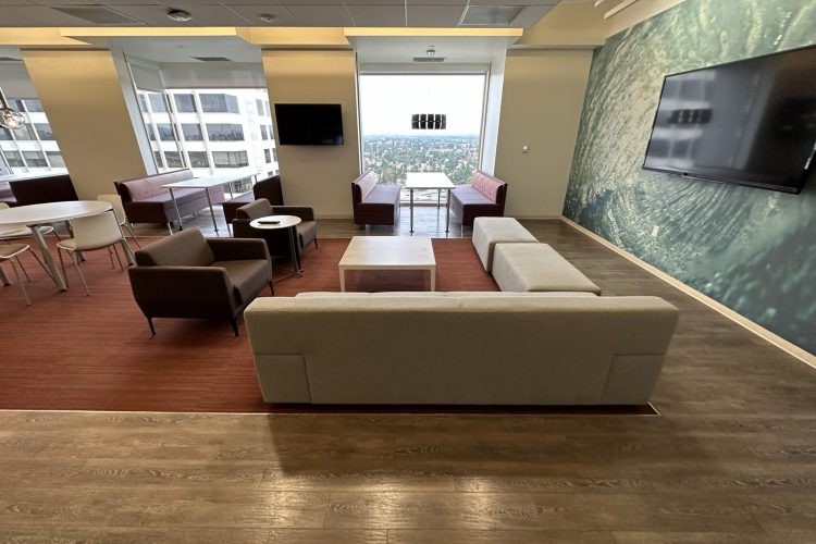 Spacious office lounge featuring contemporary furniture, large windows, and scenic cityscape views.