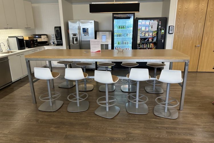 Modern break room with kitchen, vending machines, and seating area for employees.