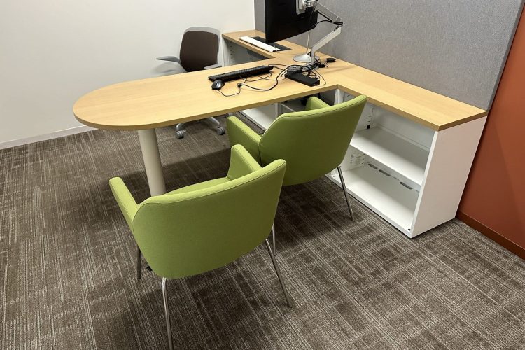 Office desk with computer setup and seating for meetings or consultations.