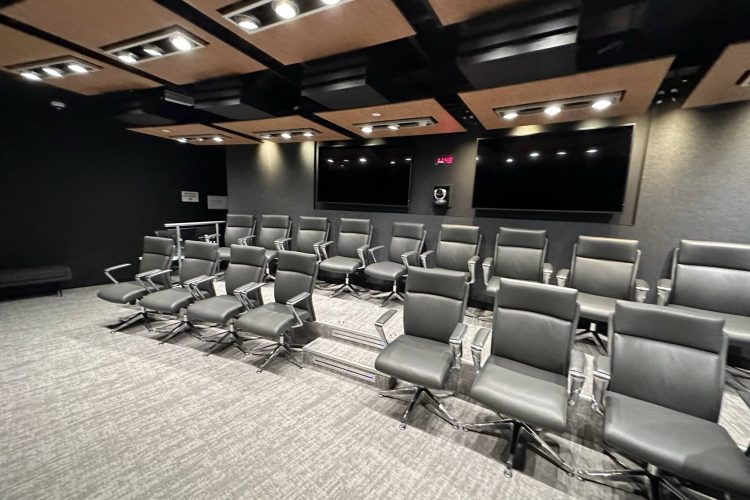 Professional conference room with sleek black chairs and large screens for presentations.