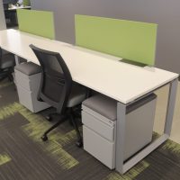 Office desks with ergonomic chairs and green privacy panels.