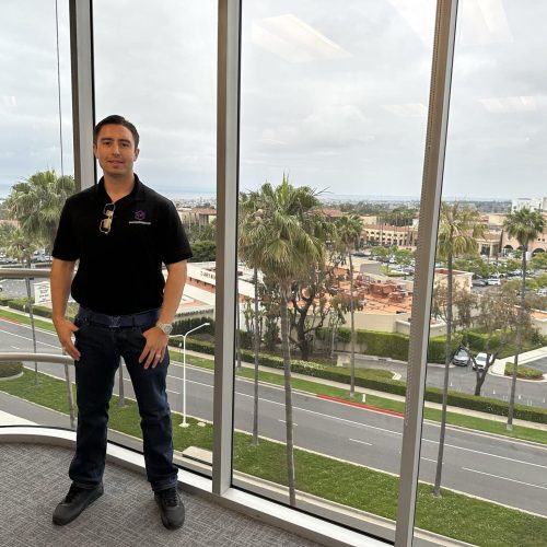 Business professional standing in modern office with city view in the background.