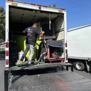 Portable shipping container with a worker loading equipment inside.
