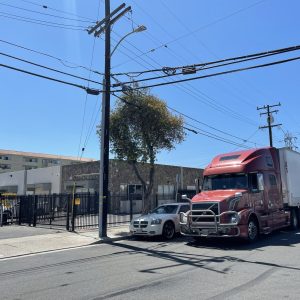 Large red semi-truck parked outside Cube World USA shipping warehouse.