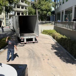 Moving truck unloading at office during facility relocation in Cube World USA.