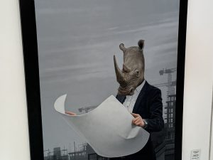 Office furniture rental artwork featuring a person with a rhino mask holding blueprints.