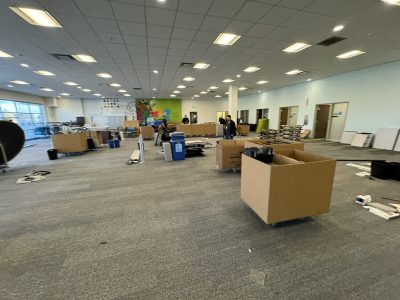 Office furniture liquidation event with desks, chairs, and cubicles in a spacious showroom.