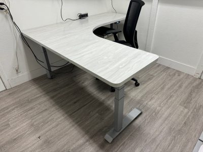 Office furniture liquidation: modern white desk with black ergonomic chair in a clean, minimal works.