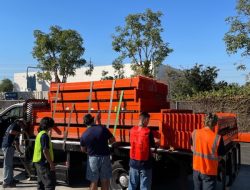 Loading orange safety barriers for facility relocation project.