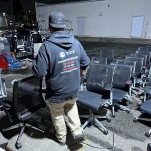 Technician installing office chairs outdoors at Cube World USA.