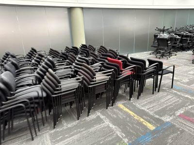 Stacked office chairs and desks at Cube World USA liquidation sale.