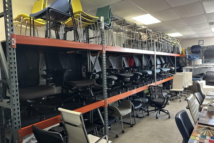 Office furniture storage with stacked chairs on industrial shelving.