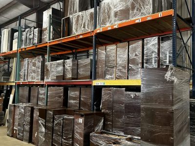 Warehouse storage shelves with office furniture in a large industrial space.