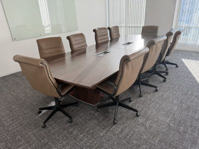 Modern office conference table with brown leather chairs in a bright meeting room.