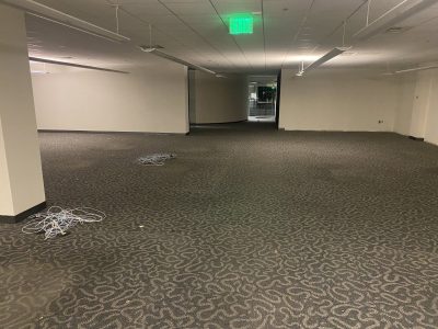 Office furniture liquidation in an empty commercial space with carpeted floors and minimal furnishin.