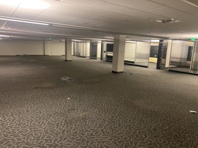 Empty office space with removed furniture and open floor plan.