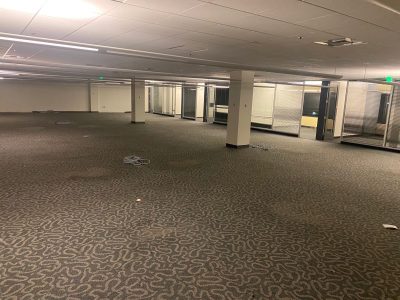 Empty office space with removed furniture and open floor plan.
