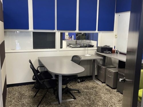 Office meeting room with blue soundproof panels, desk, and seating for professional discussions.
