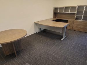Modern office desk with storage and a round meeting table in a professional workspace.