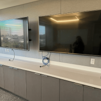 Modern conference room with two large screens and sleek cabinetry.