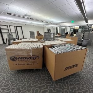 Office furniture liquidation with packed boxes and shelving units in a commercial space.