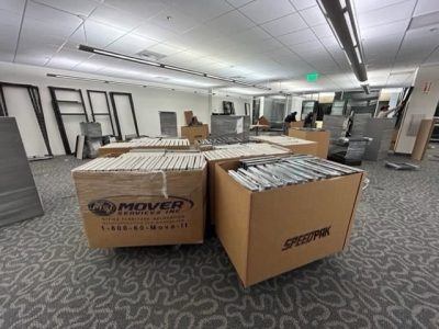 Office furniture liquidation with packed boxes and shelving units in a commercial space.